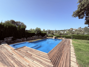 Piscina grande con amplio solárium de madera y zona de césped en chalet independiente en Las Pajanosas, Guillena