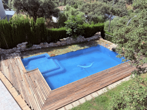 Vista aérea de piscina privada con tarima de madera y jardines en chalet independiente en Las Pajanosas, Guillena.
