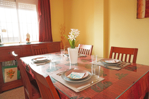Comedor con mesa de cristal, sillas y aparador de madera en chalet adosado en Alcalá del Río