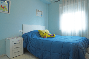 Dormitorio individual con cama, mesita de noche y ventana en chalet adosado en Alcalá del Río