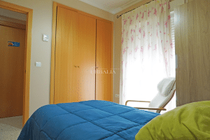 Dormitorio con cama y armario empotrado de madera clara en chalet en venta en Alcalá del Río, en calle Almería.