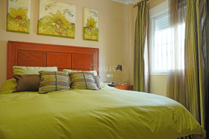 Dormitorio principal con cama doble, cabecero de madera y ventana luminosa en chalet en Alcalá del Río