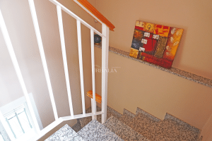 Escaleras de granito con barandilla blanca y pasamanos de madera en chalet adosado en Alcalá del Río