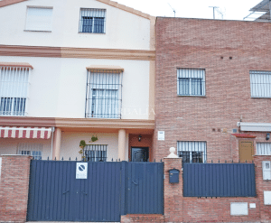 Fachada exterior de chalet adosado en venta en Alcalá del Río con puerta de garaje y entrada principal