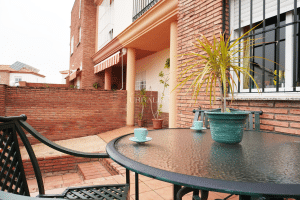 Patio delantero con mobiliario de exterior y fachada de ladrillo en chalet adosado en Alcalá del Río