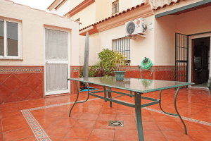 Patio trasero amplio con suelo de terracota, mesa exterior y acceso a salón en chalet en Alcalá del Río