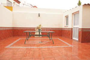 Patio trasero exterior con mobiliario, fuente decorativa y suelo de baldosas en chalet en Alcalá del Río