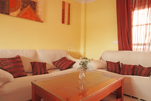 Zona de salón con sofás cómodos y mesa de centro de cristal en chalet en Alcalá del Río.
