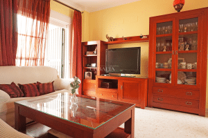 Zona de TV y mueble de salón con vajillero, sofá y acceso a patio en chalet en Alcalá del Río.