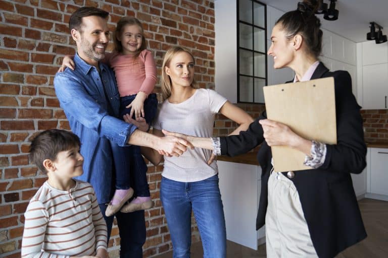 Familia estrecha la mano de agente inmobiliario al comprar una vivienda en Sevilla.