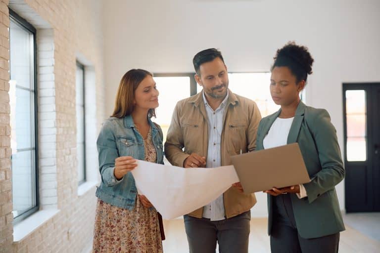 Pareja con un agente inmobiliario revisando planos para comprar una vivienda de segunda mano en Sevilla.