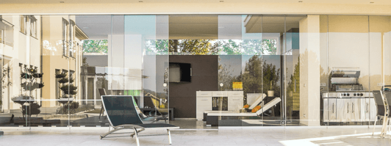 Lujo y Comodidas al Aire Libre El patio trasero de una casa moderna con una piscina, una terraza con muebles de exterior y una cocina al aire libre.