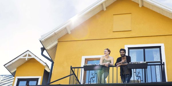 Pareja sonriente en balcón de una casa de segunda mano en Sevilla.